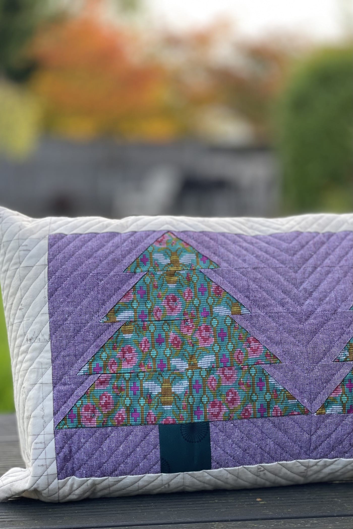 Purple and green pillow with patchwork pieced evergreen trees outdoors