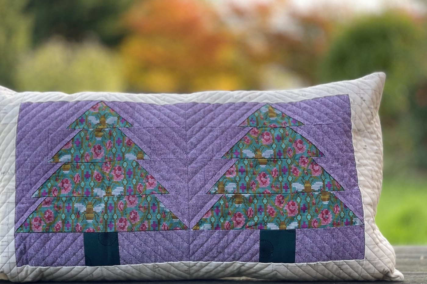 Purple and green pillow with patchwork pieced evergreen trees outdoors