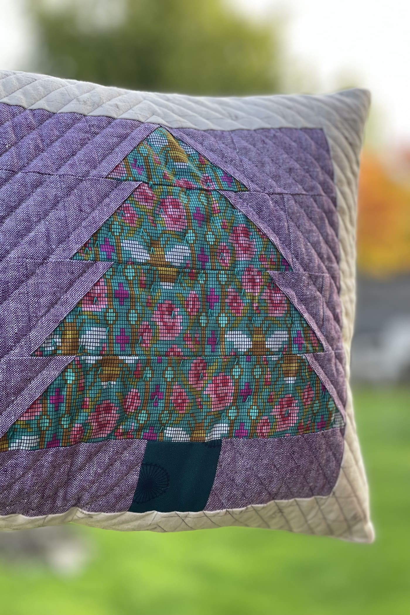 Purple and green pillow with patchwork pieced evergreen trees outdoors