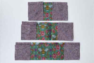 purple and green fabric on white tabletop cut into squares and triangles