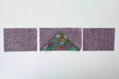 purple and green fabric on white tabletop cut into squares and triangles