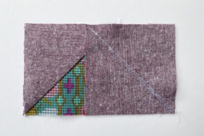 purple and green fabric on white tabletop cut into squares and triangles