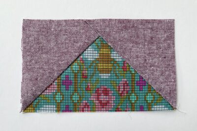 purple and green fabric on white tabletop cut into squares and triangles