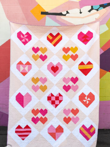 pink heart quilt in front of colorful wall