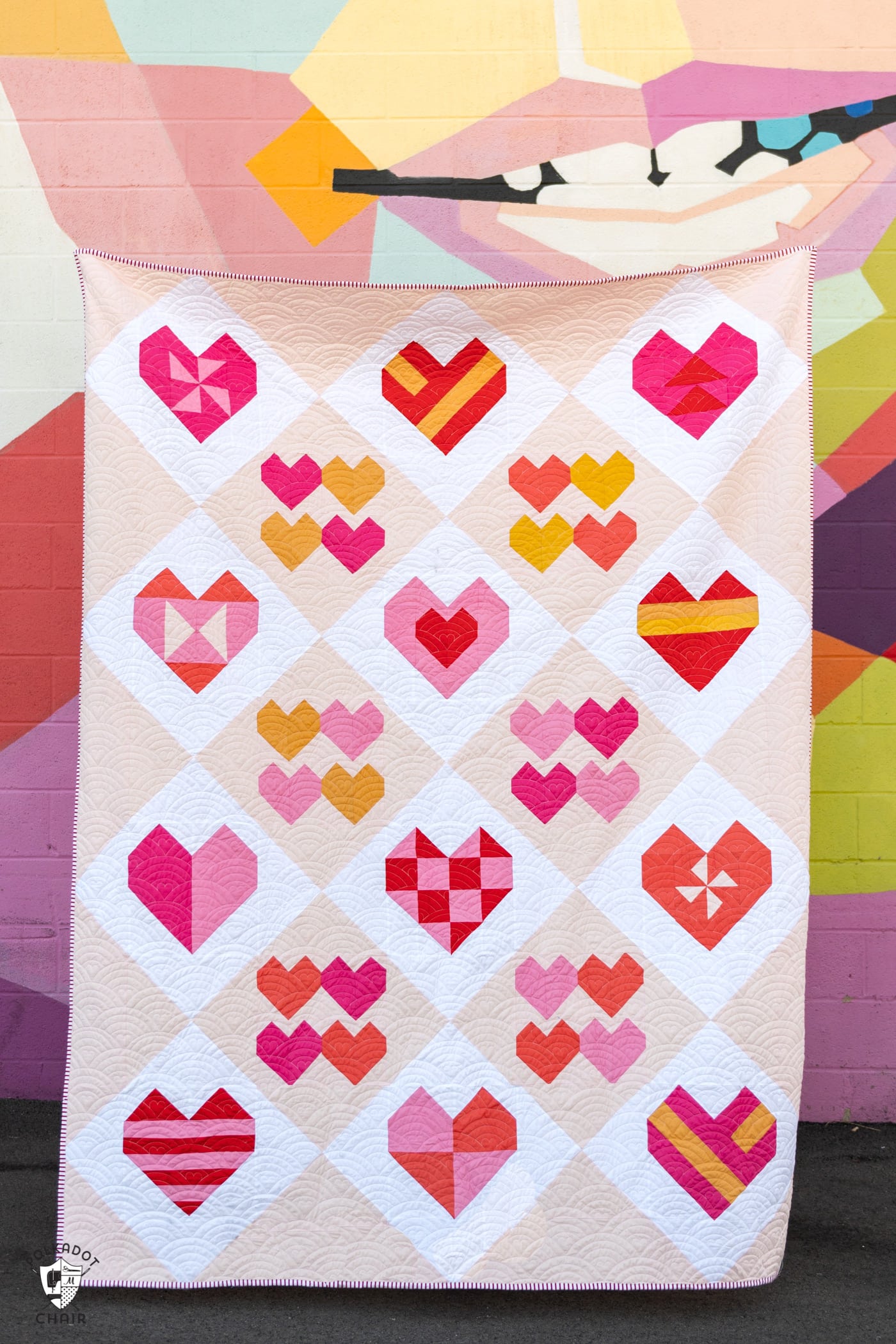 pink heart quilt in front of colorful wall