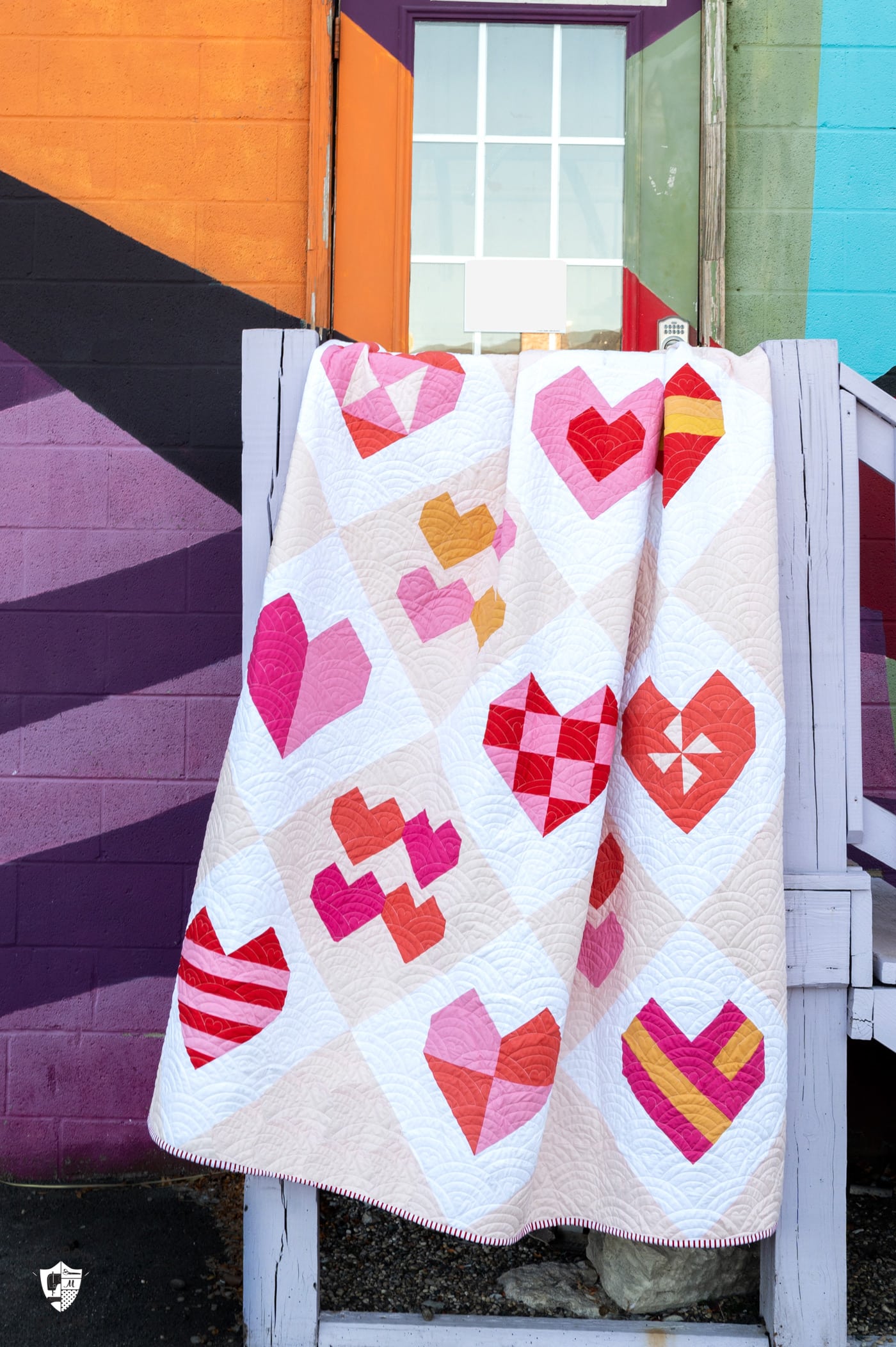 pink heart quilt in front of colorful wall on railing