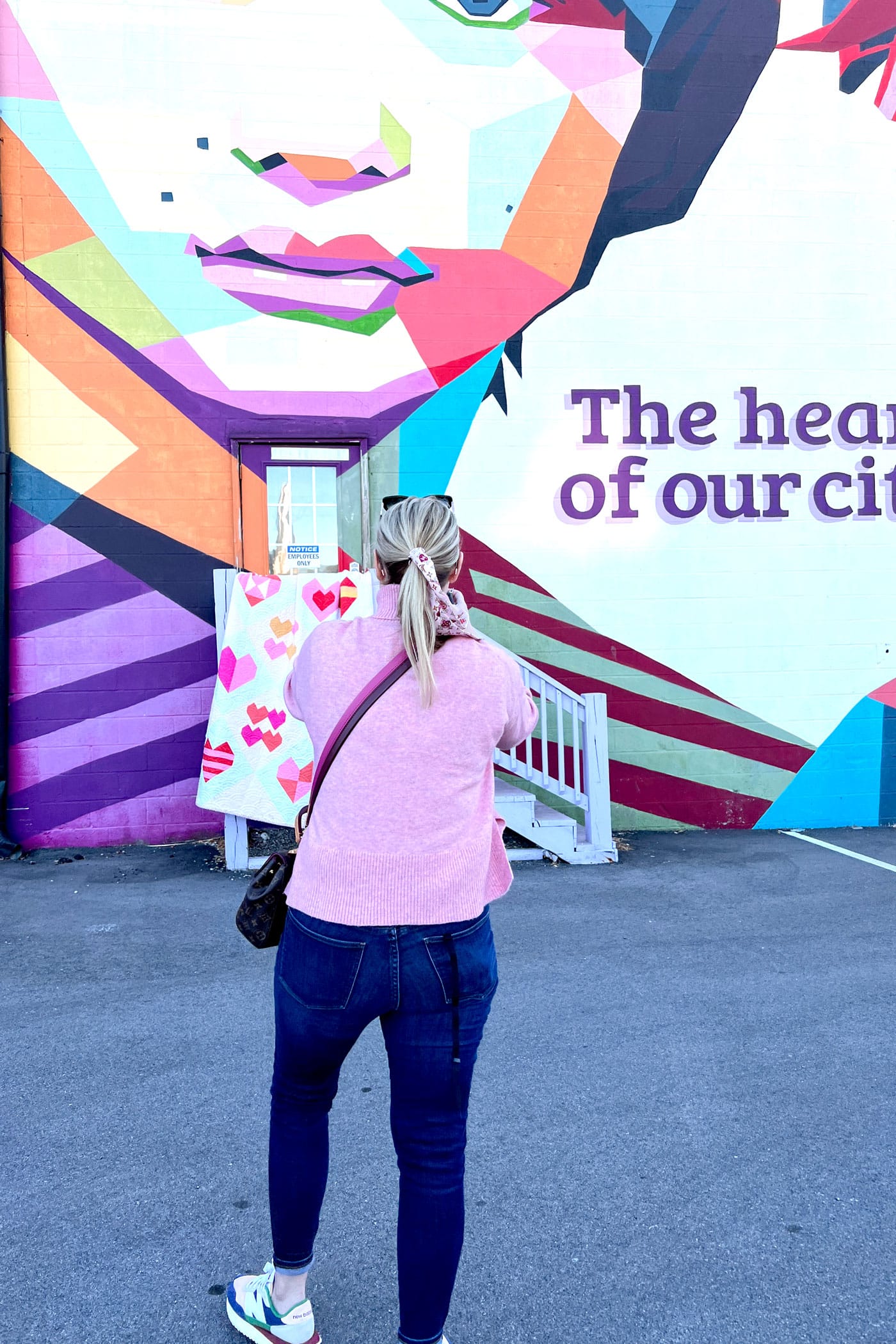 woman photographing quilt in front of mural