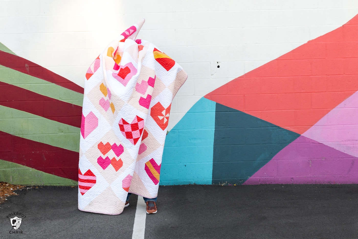 pink heart quilt in front of colorful wall