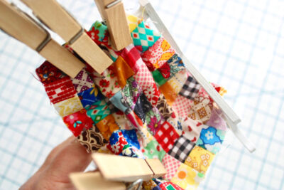 fabric scraps sewn into mini quilt with clothespins