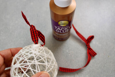 string ornament and bottle of tacky glue on gray table