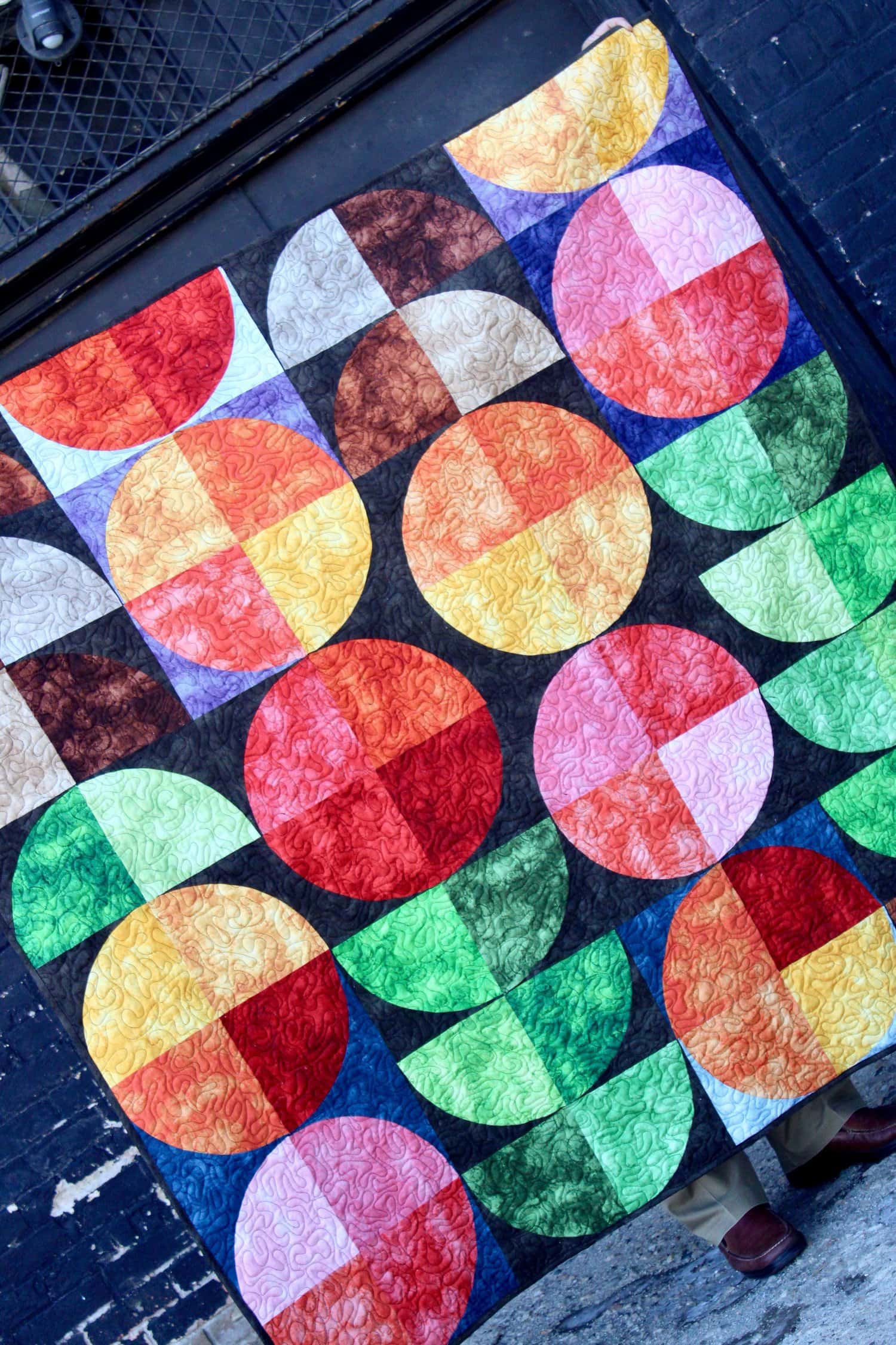 colorful quilt made from circles and half circles in batik fabrics