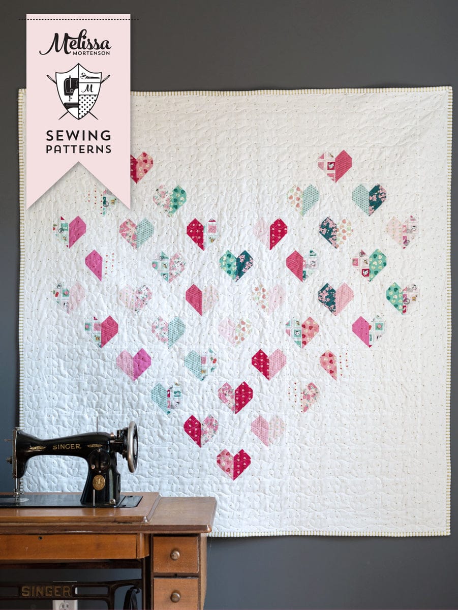 quilt hanging on gray wall with heart quilt blocks