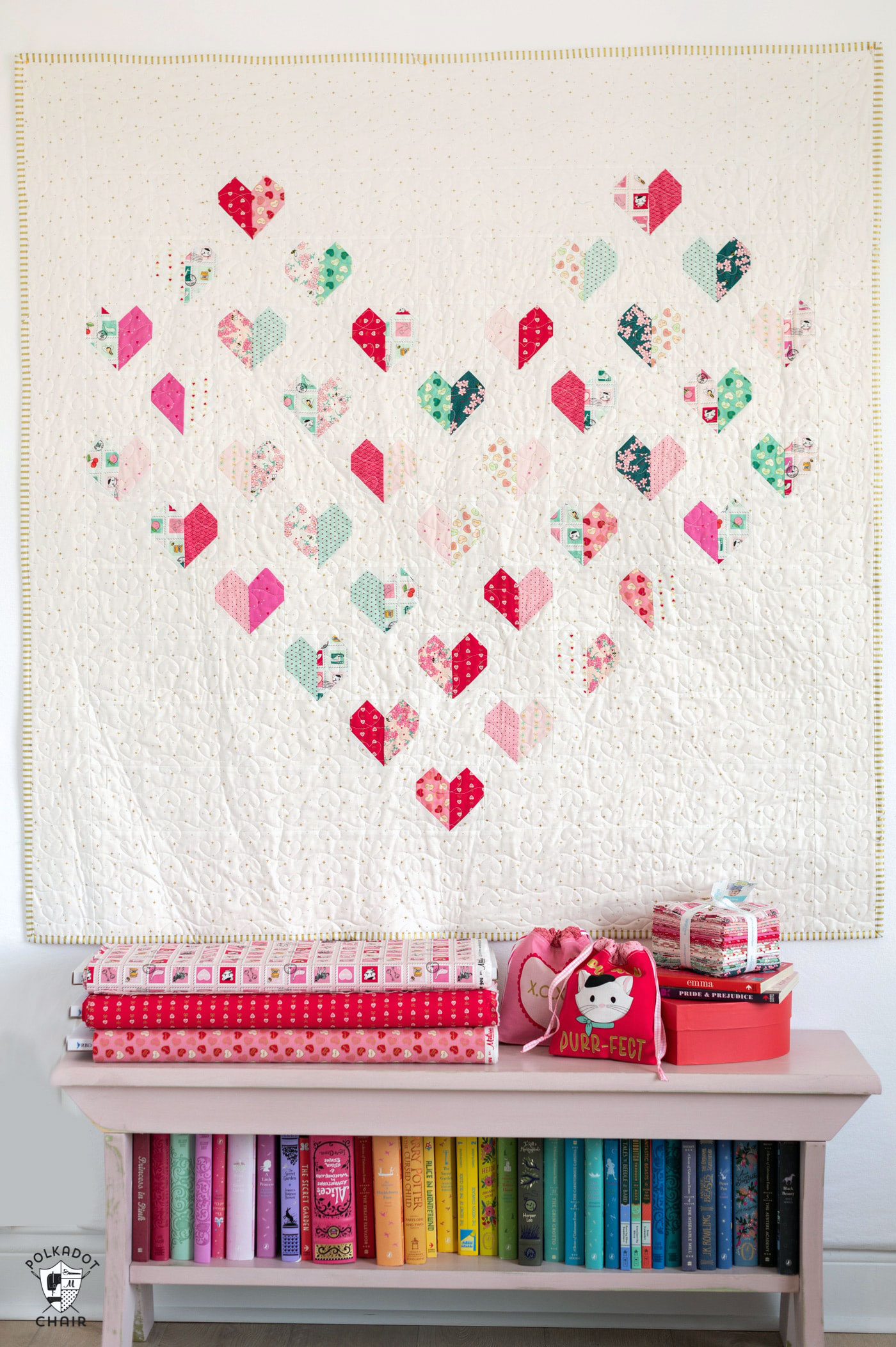 heart quilt hanging on wall with bench featuring colorful books