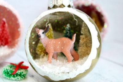 retro ornaments with deer, trees and glitter snow on white wood table