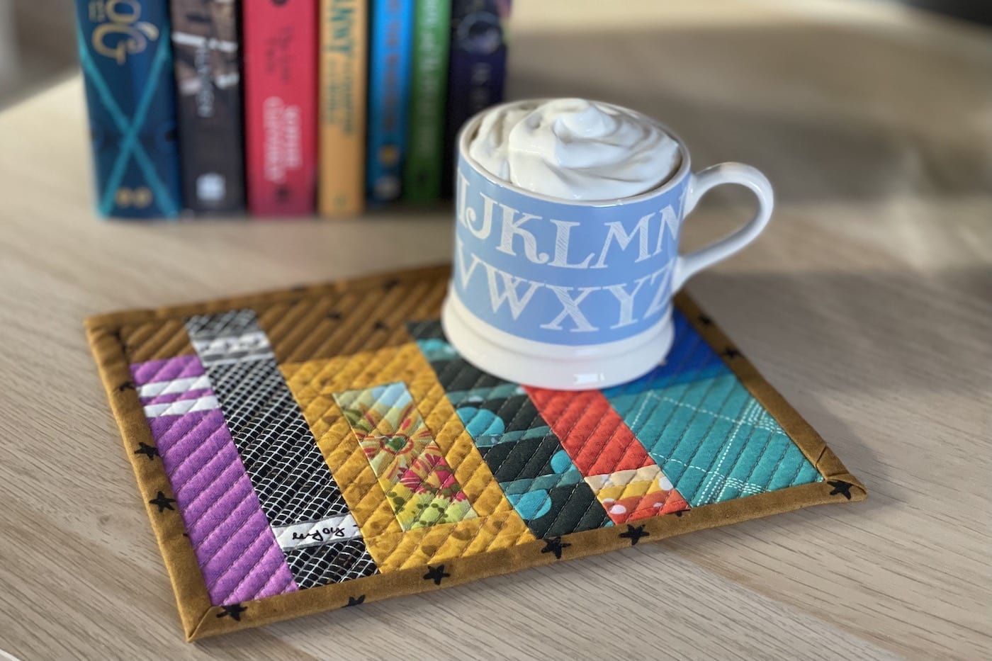 Mug rug and mug with ship cream and cocoa with books on wood table