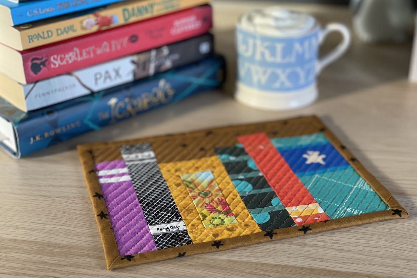 Mug rug and mug with ship cream and cocoa with books on wood table