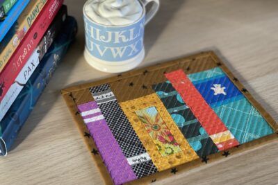 Mug rug and mug with ship cream and cocoa with books on wood table