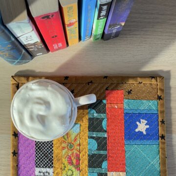Mug rug and mug with ship cream and cocoa with books on wood table