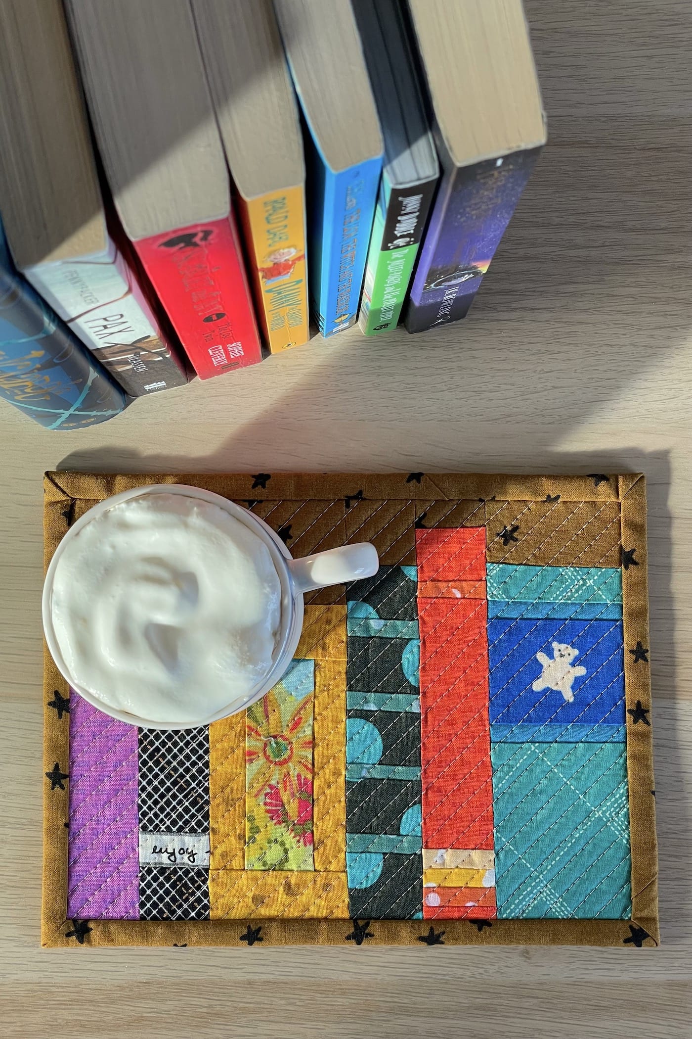 Mug rug and mug with ship cream and cocoa with books on wood table