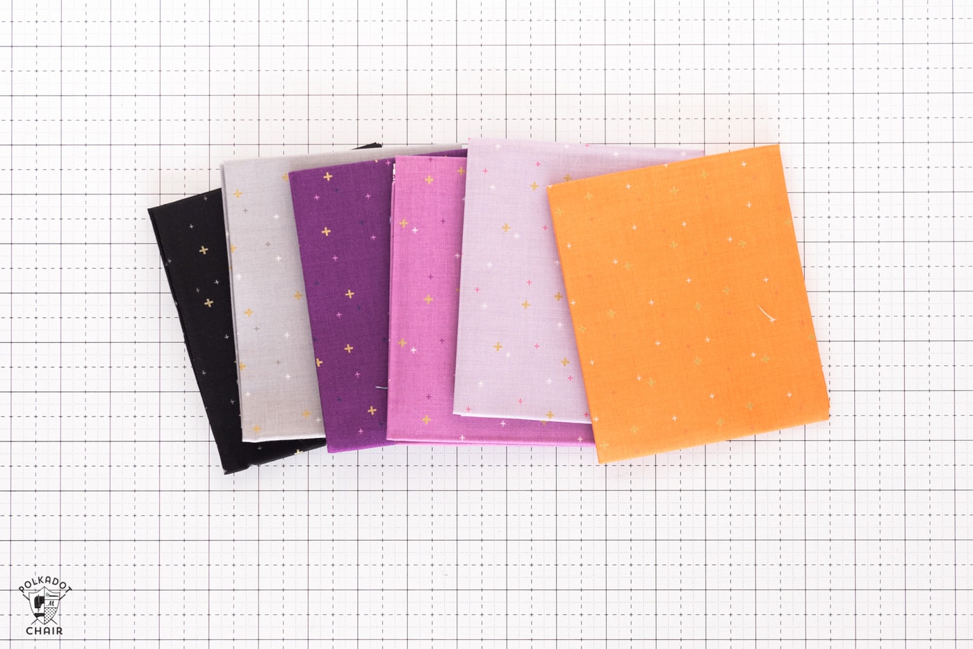 stack of colorful folded fabrics on white cutting mat