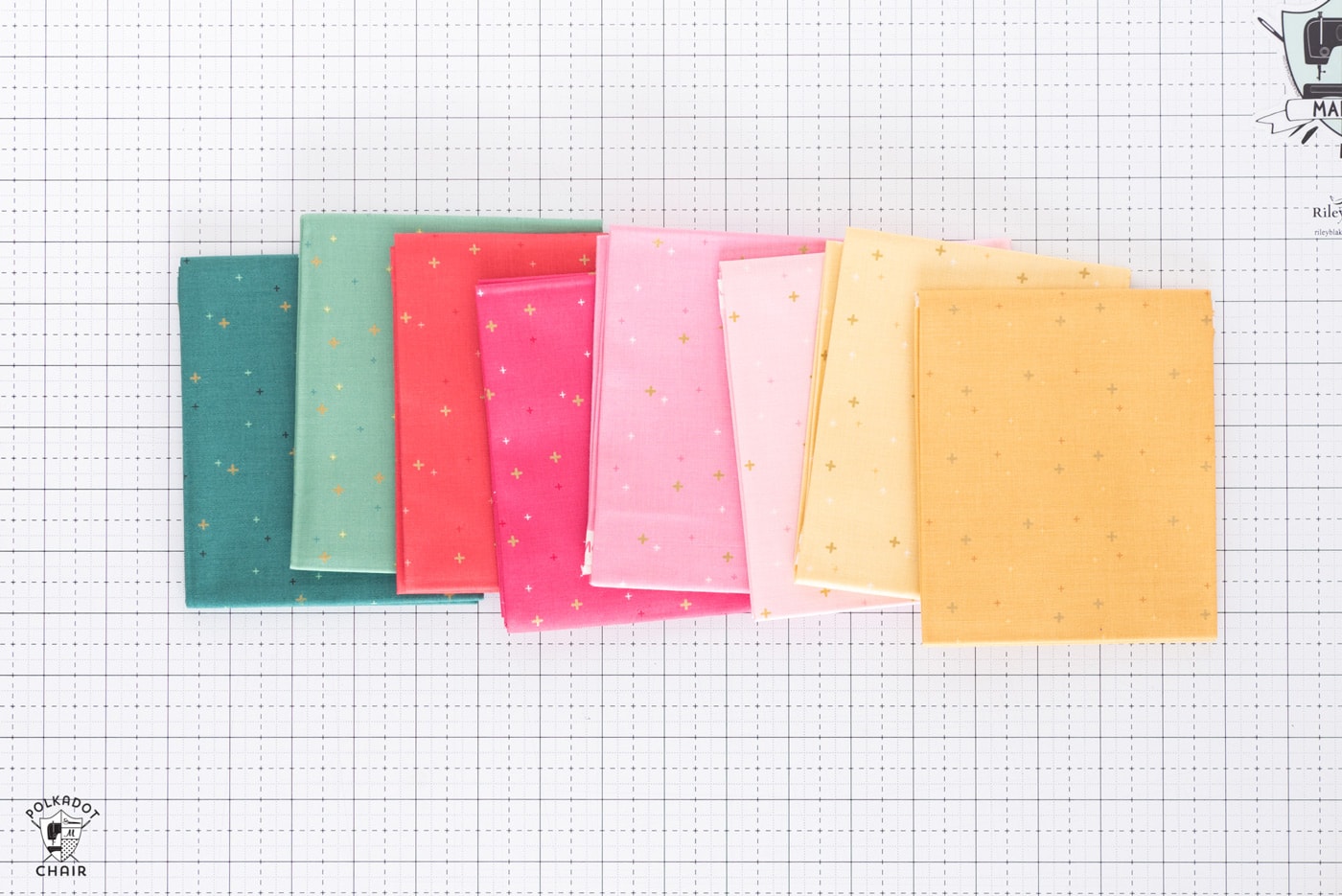 stack of colorful folded fabrics on white cutting mat