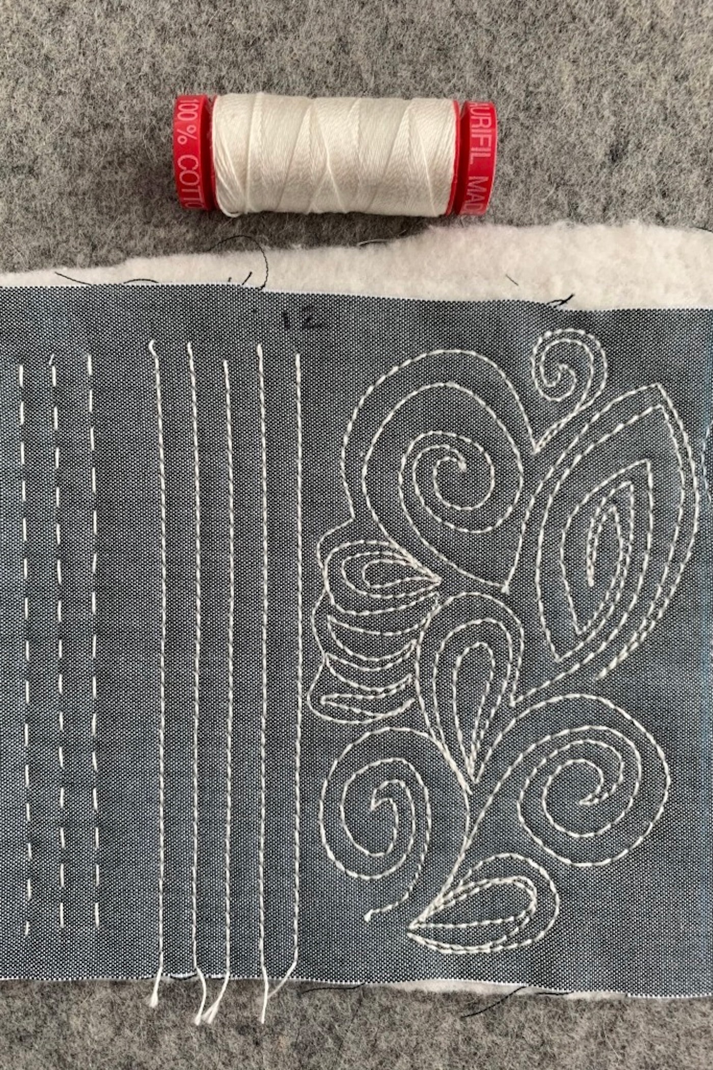 close up of ivory thread on gray fabric, machine quilted