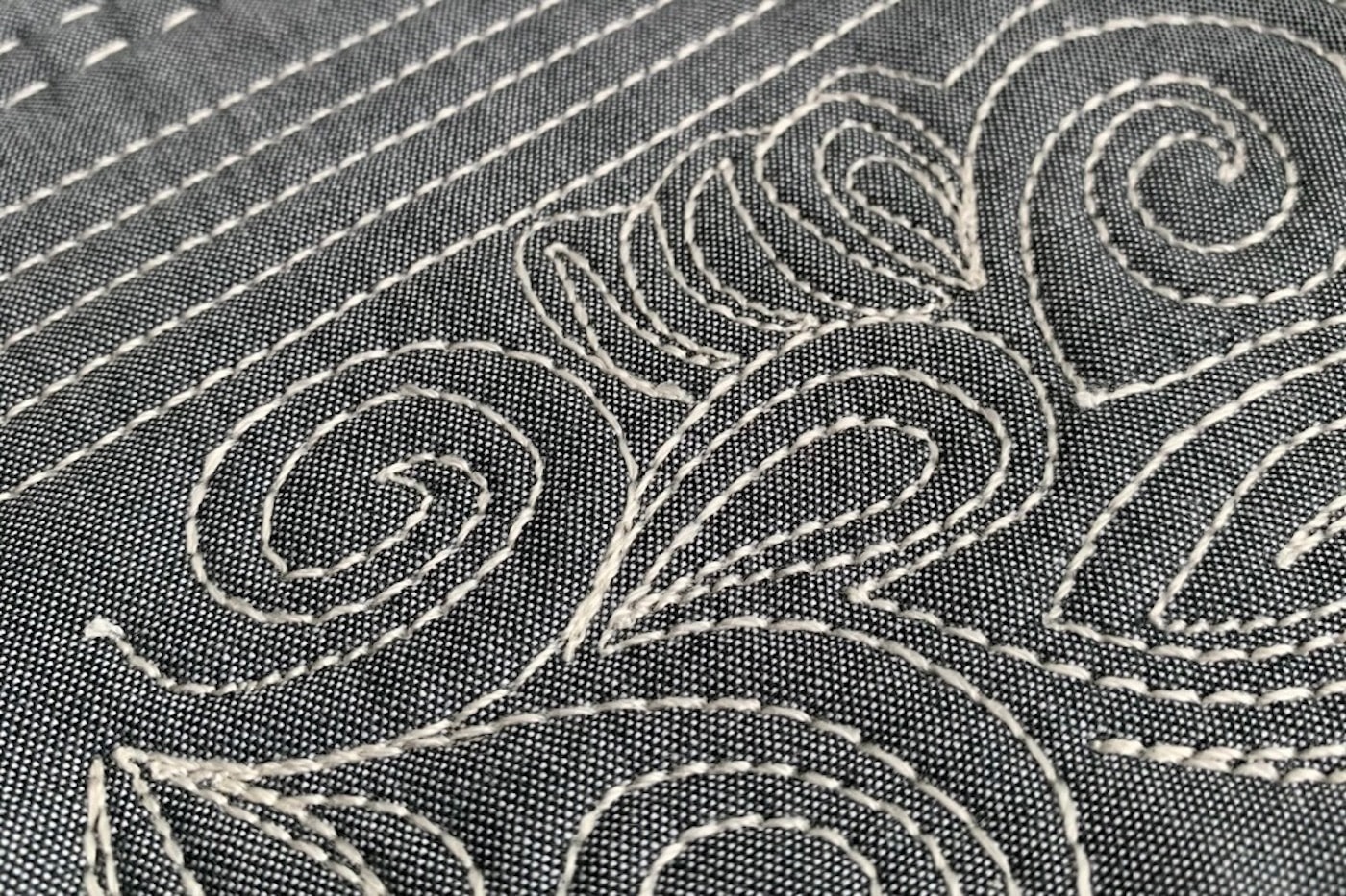 close up of ivory thread on gray fabric, machine quilted