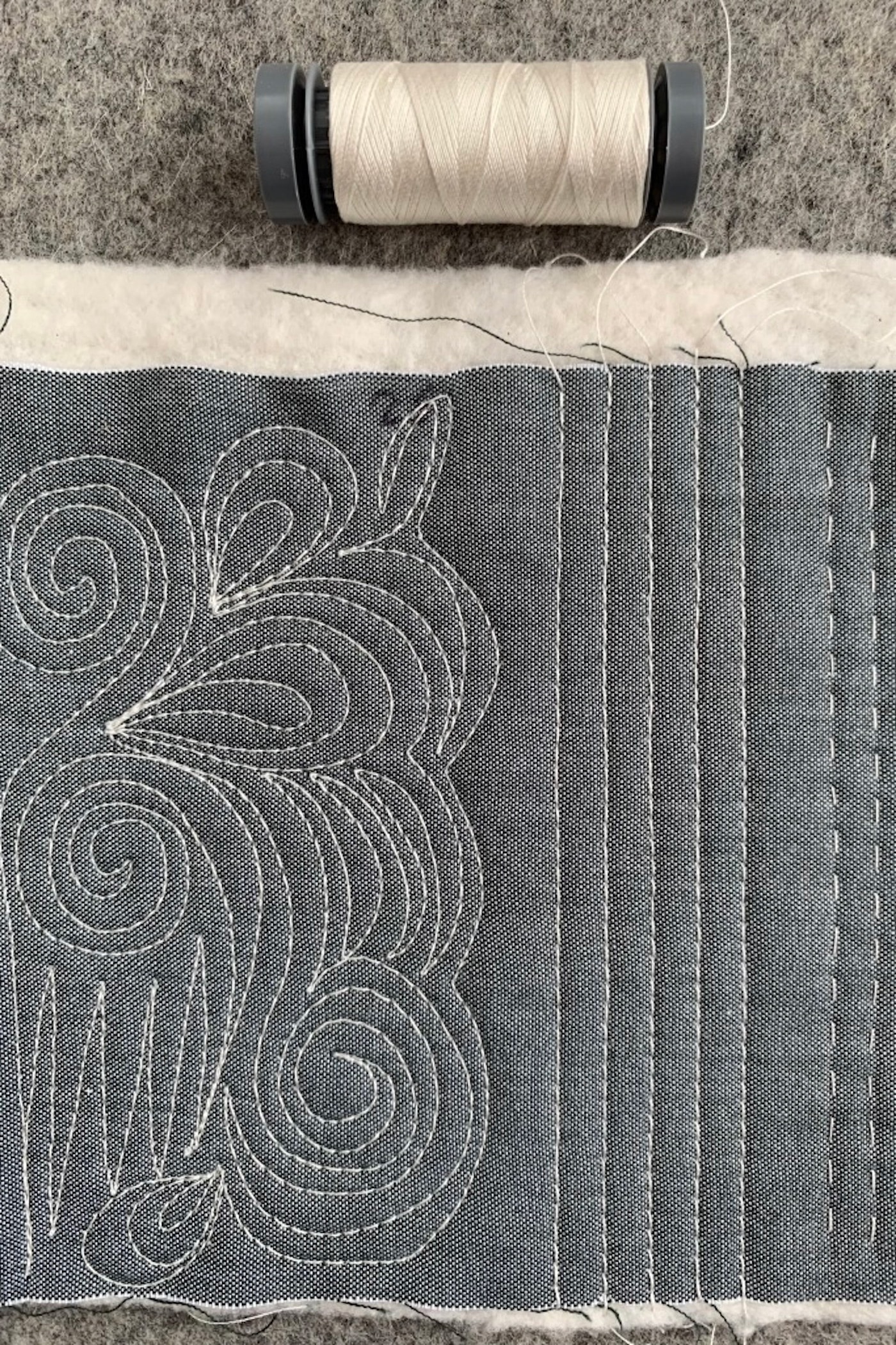 close up of ivory thread on gray fabric, machine quilted