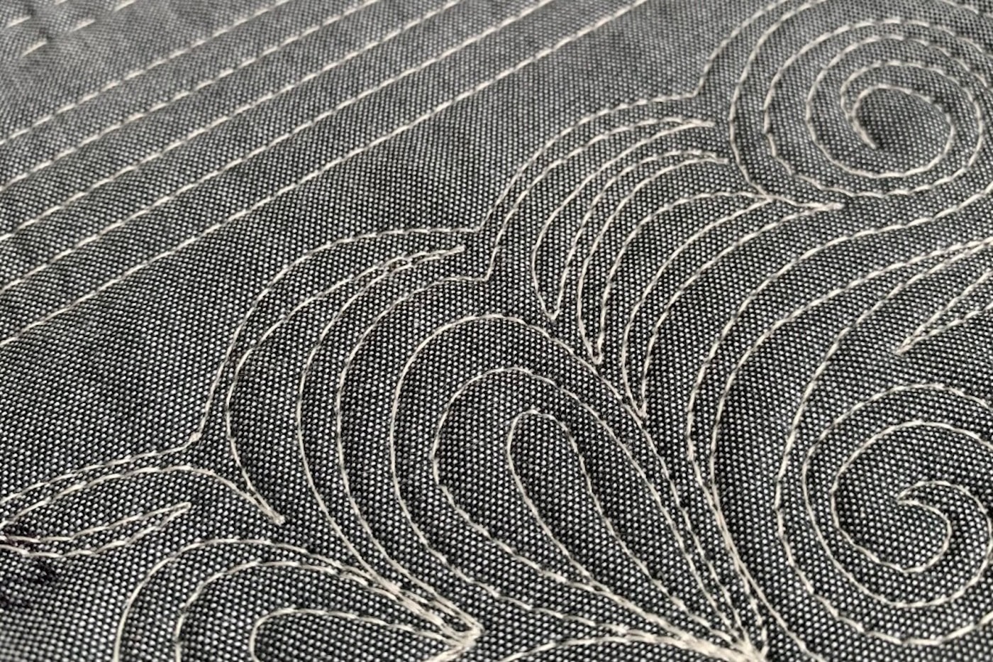 close up of ivory thread on gray fabric, machine quilted