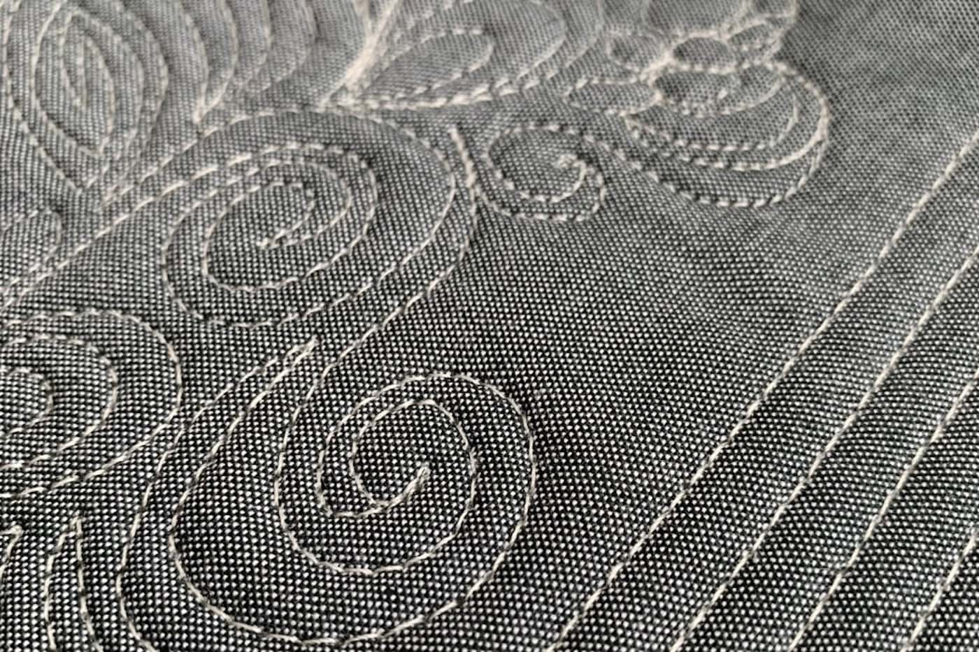 close up of ivory thread on gray fabric, machine quilted