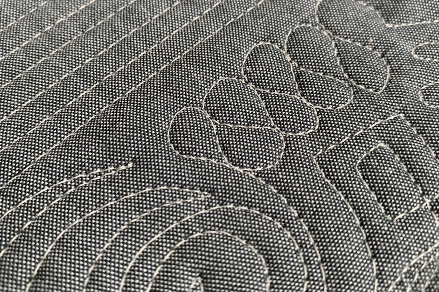 close up of ivory thread on gray fabric, machine quilted