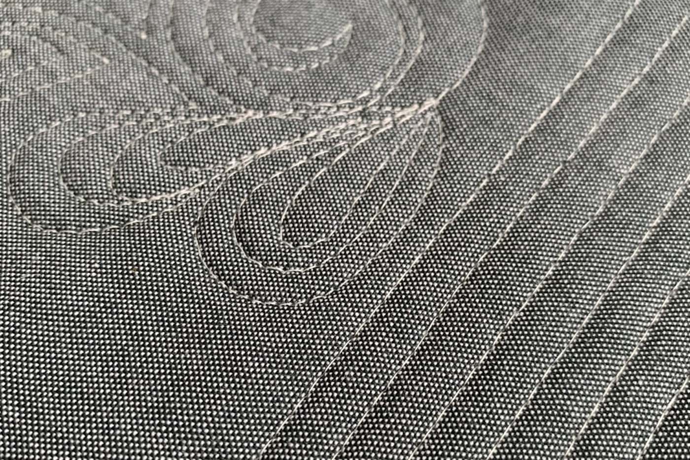 close up of ivory thread on gray fabric, machine quilted