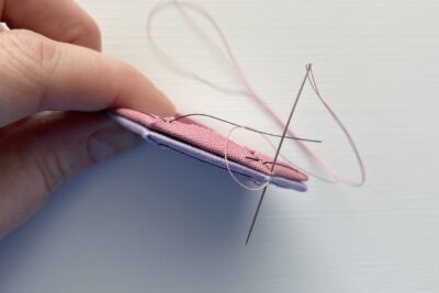 needle showing two pieces of fabric begin sewn together