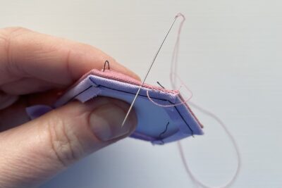 needle showing two pieces of fabric begin sewn together