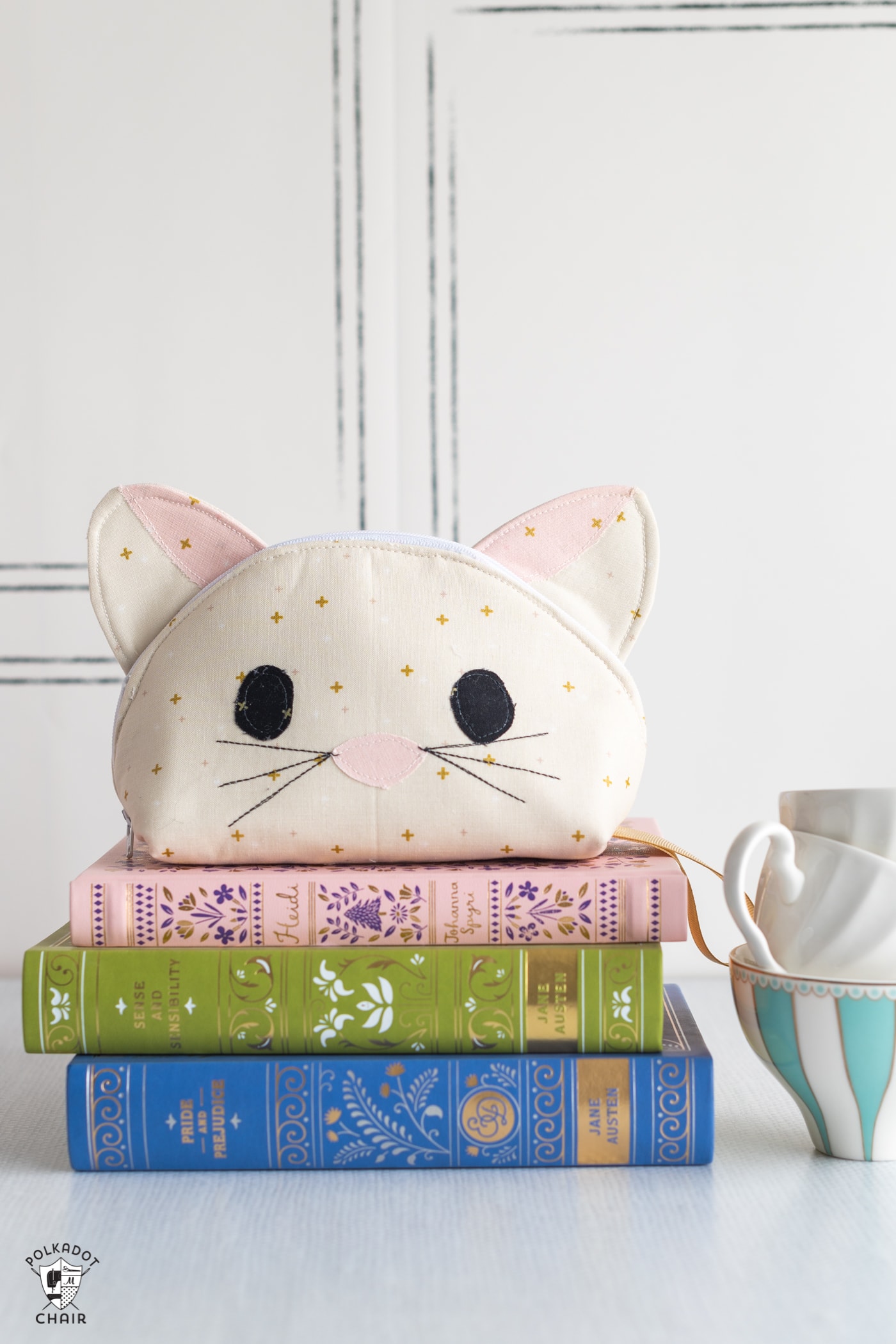 cat zip bag with face on stack of books