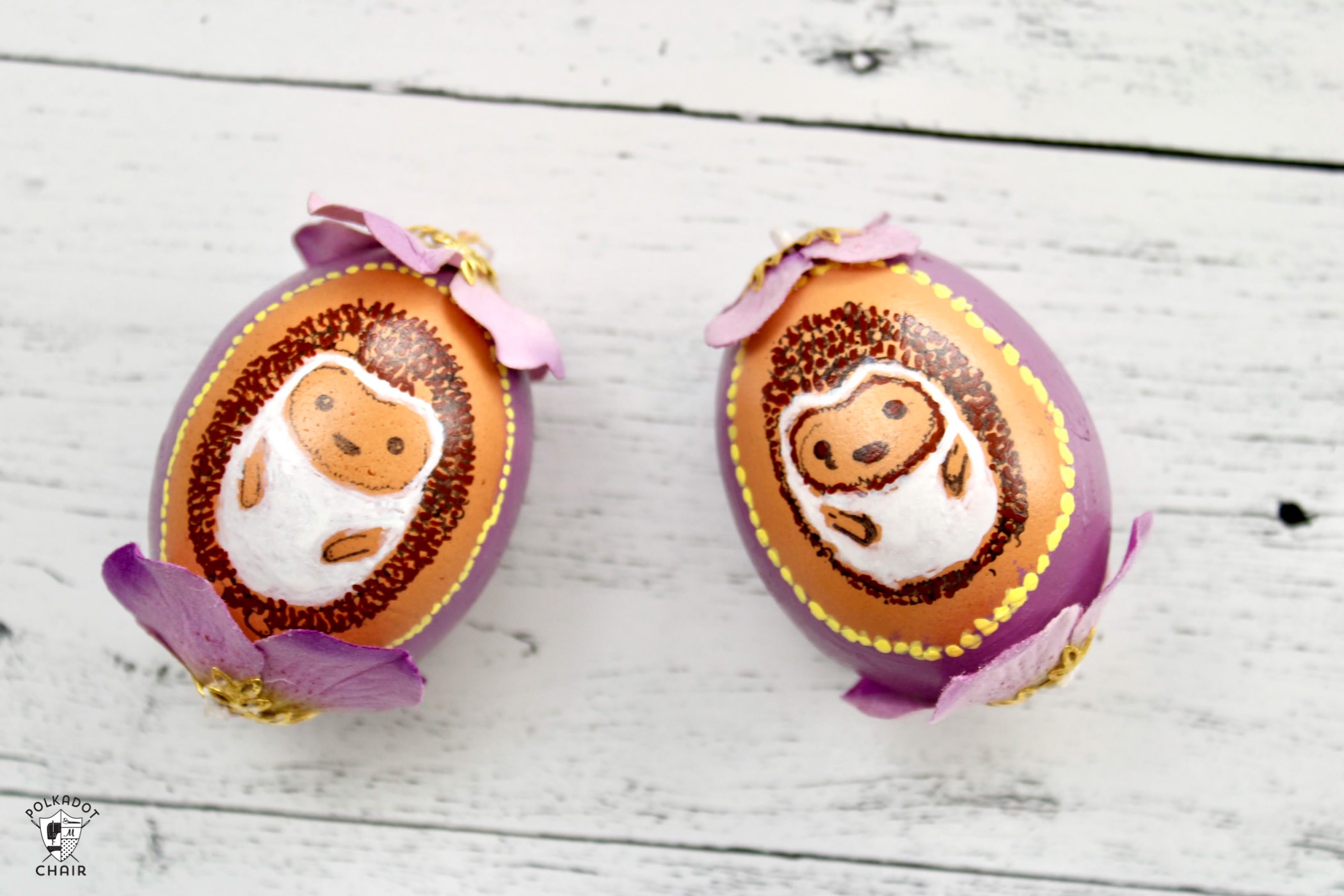 multiple blown egg ornaments with painted hedgehogs on white wood table