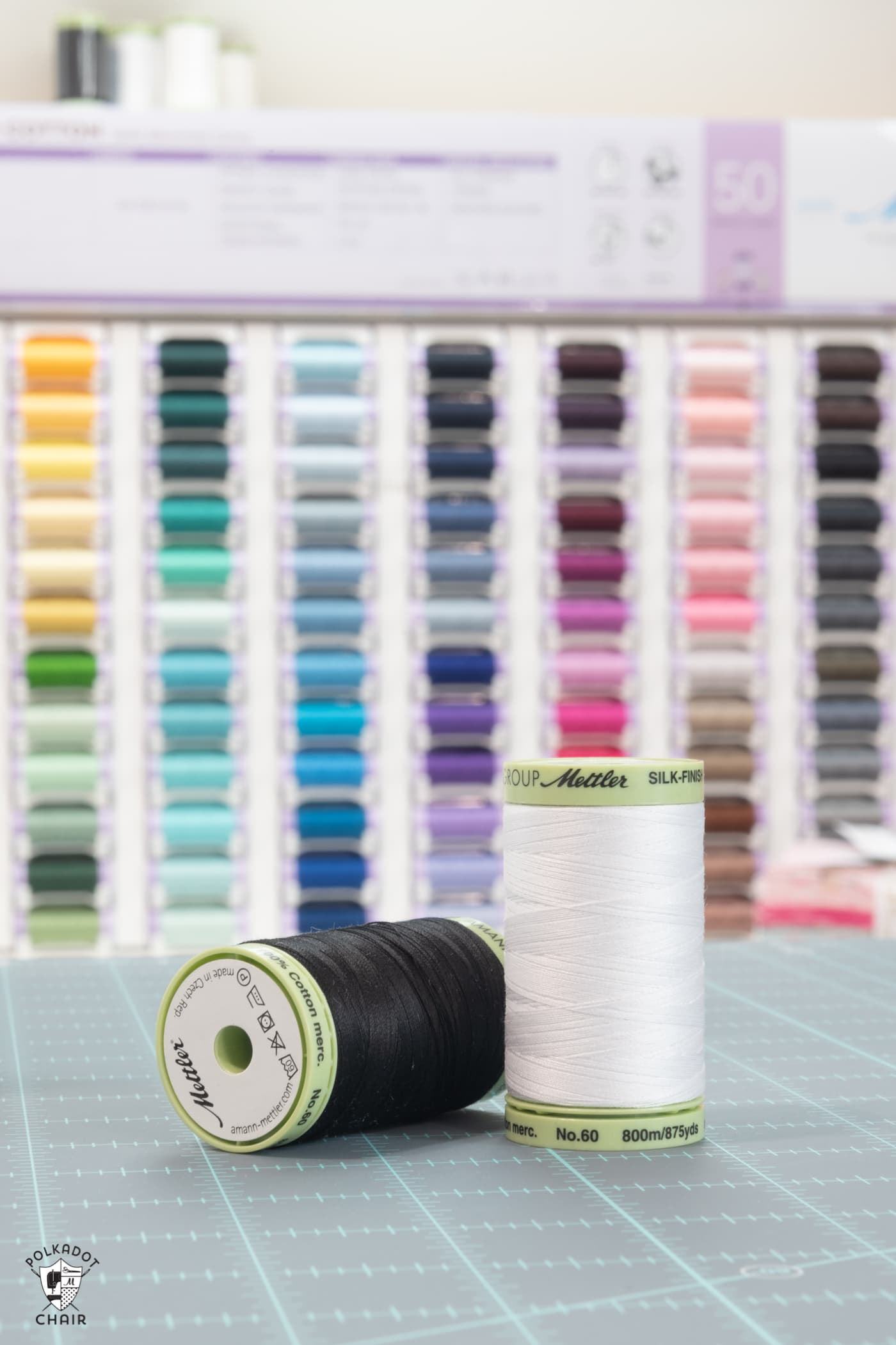 two thread spools on cutting mat in front of thread case