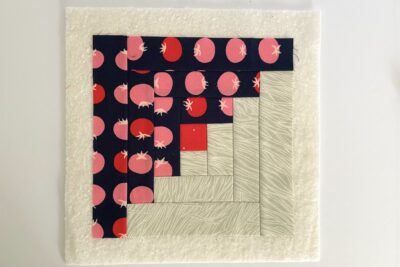 log cabin quilt block in construction showing blue, red and ivory fabrics