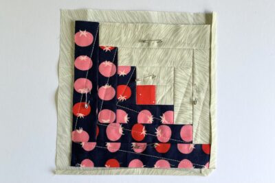 log cabin quilt block in construction showing blue, red and ivory fabrics