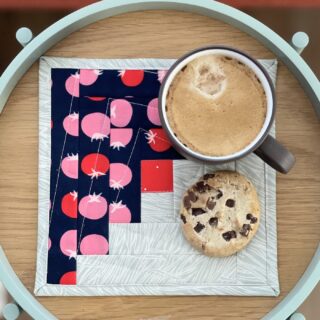 navy and ivory log cabin mug rug on wood tray with coffee and cookie