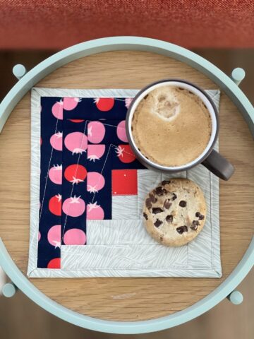navy and ivory log cabin mug rug on wood tray with coffee and cookie