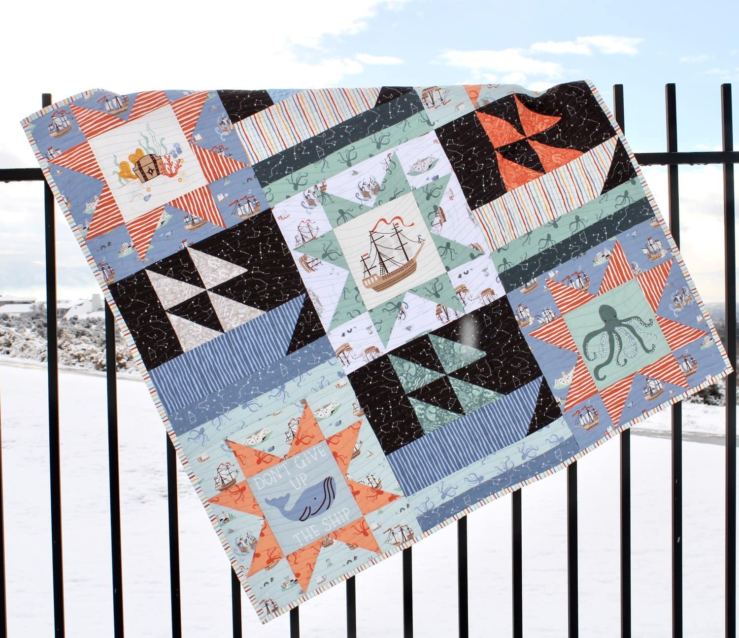 blue black and orange baby quilt on fence
