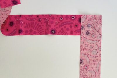 how to bind the mug rug, pink fabric on white tabletop