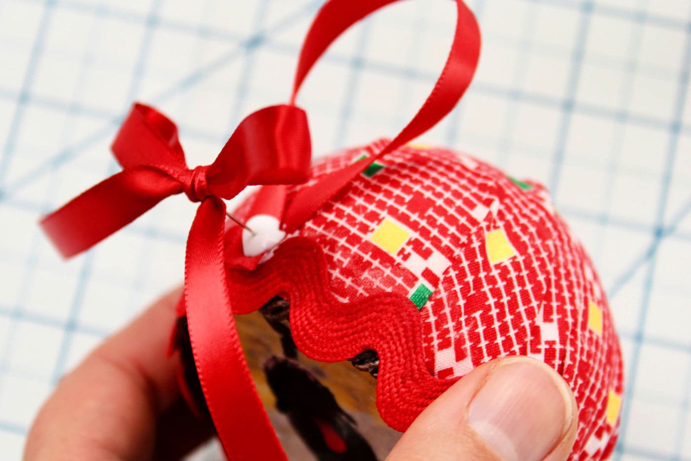 close up of round fabric ornament with trim and ribbon attached