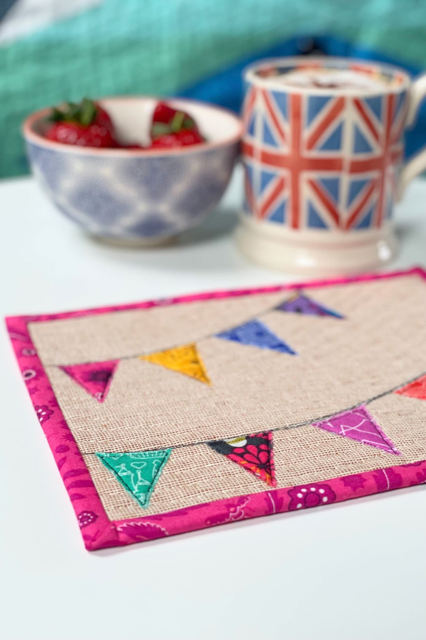 colorful mug rug and union jack mug on white tabletop