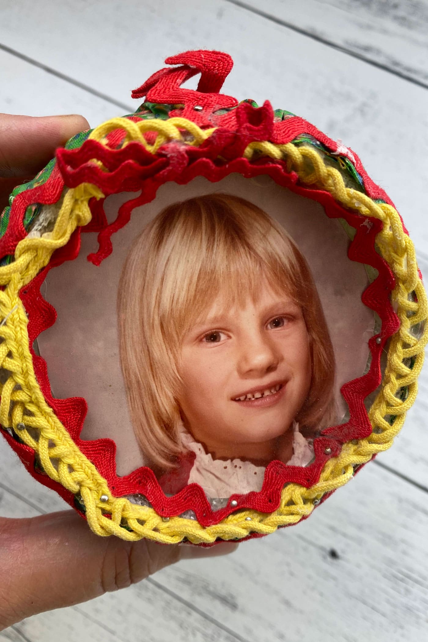 close up of round fabric ornament with trim and ribbon attached