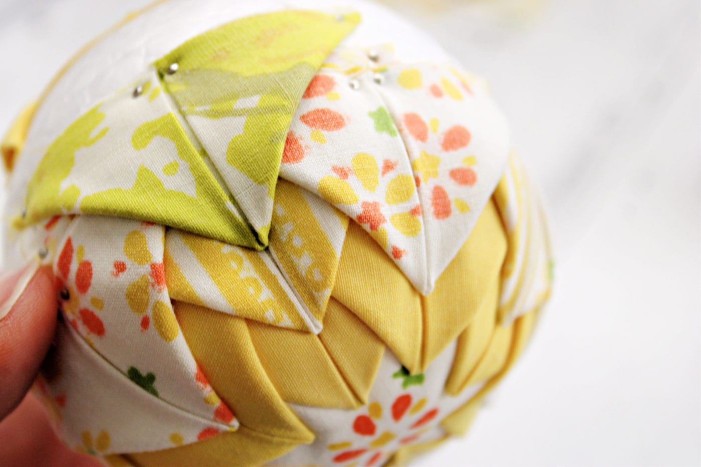 yellow and white vintage folded fabric ornament on white table with fabric scraps