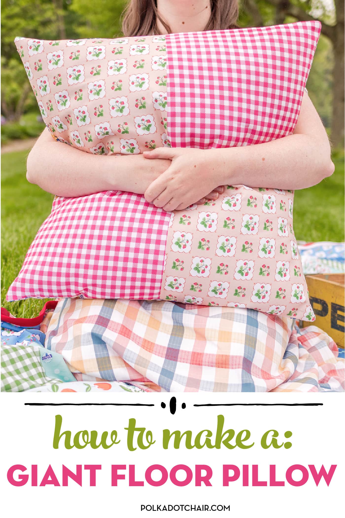 girl holding a colorful giant pillow outdoors on a picnic blanket