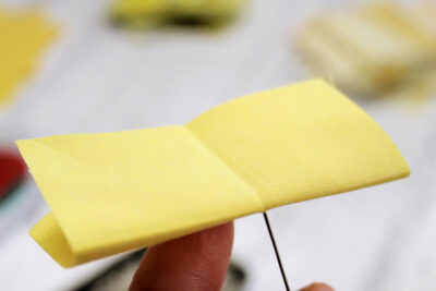 yellow fabric with folds, pin and white styrofoam ball