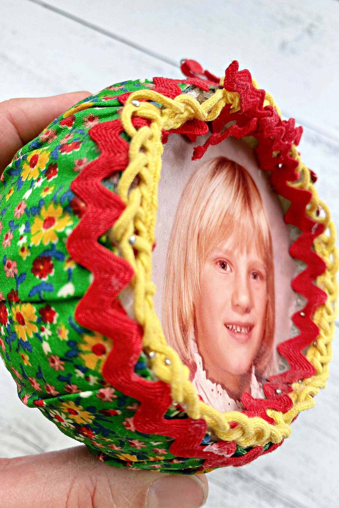 close up of round fabric ornament with trim and ribbon attached